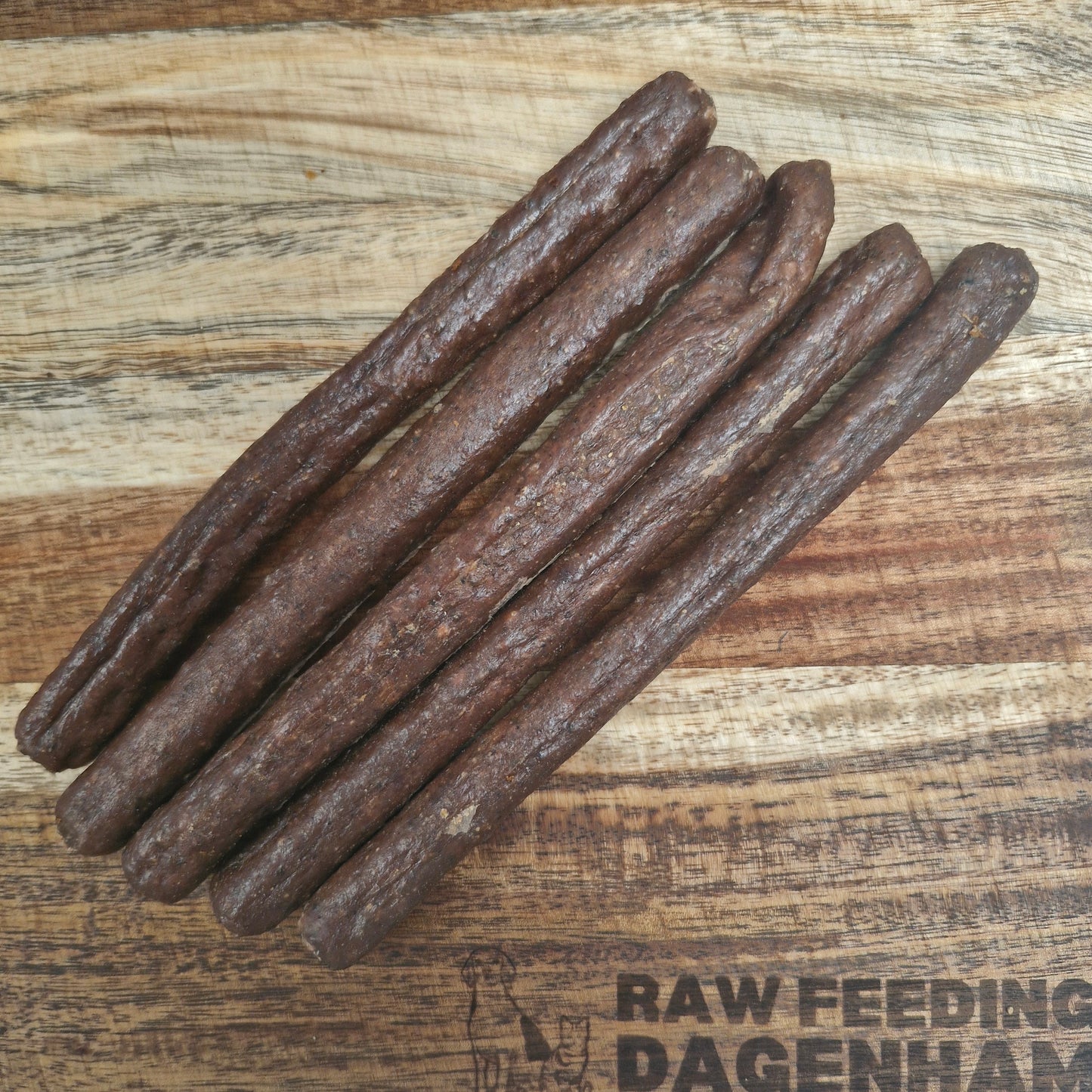 A set of gourmet pure beef sausages placed on a wooden surface, with the text 'RAW FEEDING DAGESTAN' visible.