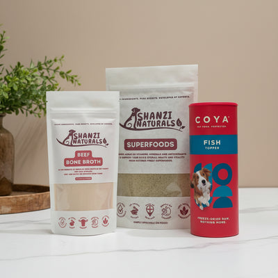 Two packages of Shanzi Naturals Superfoods and a Coya Fish Formula package on a striped background