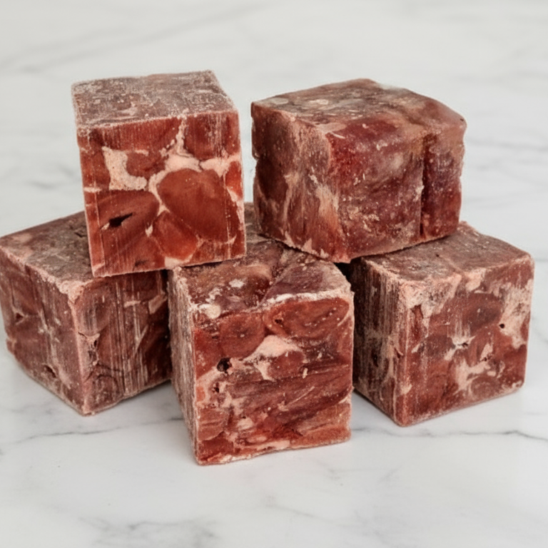 Five cubes of red meat on a white background