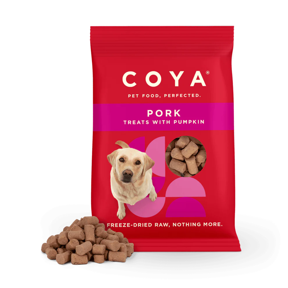 A package of COYA brand freeze-dried pork and pumpkin dog treats. The packaging is red with an image of a dog and the treats are visible in a clear window.